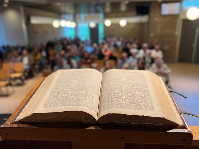 kanselbijbel HGL met kerkgangers onscherp
